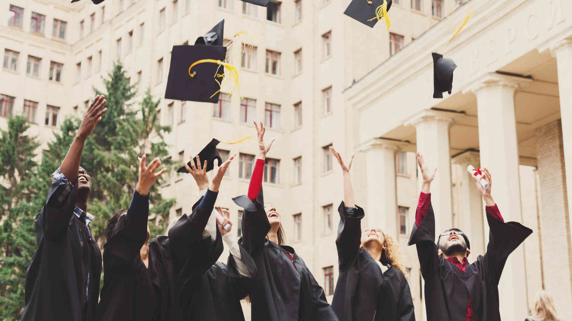 Graduates Throwing Hat Up Into The Air